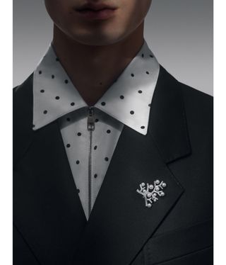 Man wearing pearl brooch and spotted shirt