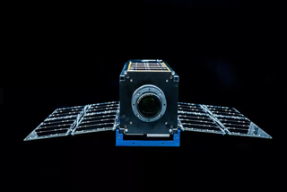  Moonlighter satellite, a small cube-shaped craft with solar panel wings on either side, against a black background.