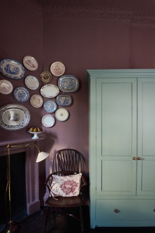 A kitchen with aubergine walls decorated with vintage plates