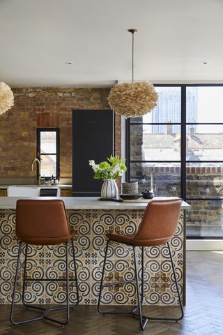 industrial style kitchen with exposed brick wall, ruffled pendant lights, tan bar stools, tiled breakfast bar, wooden floor