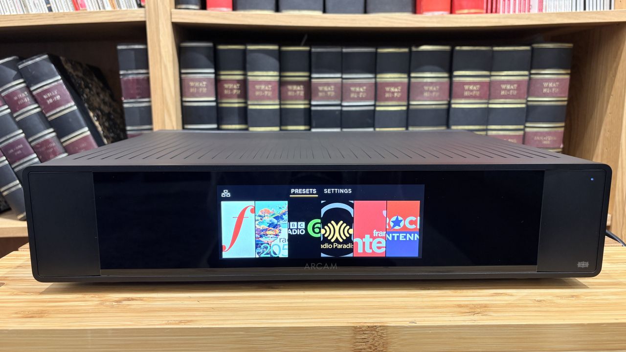 Arcam ST25 music streamer on wooden rack with bookshelf behind it