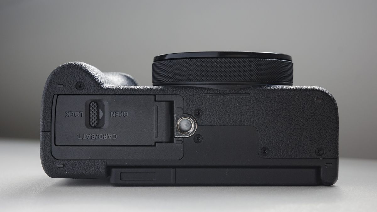 Underside of the Canon PowerShot V1 compact vlogging camera on a white desk