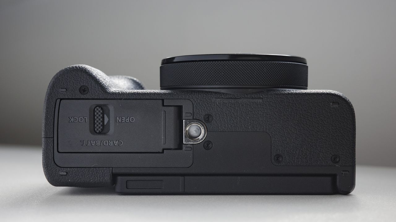 Underside of the Canon PowerShot V1 compact vlogging camera on a white desk