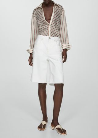 a model wears white denim Bermuda shorts