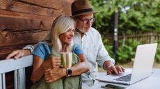 a couple talking at a table while scrolling on a laptop