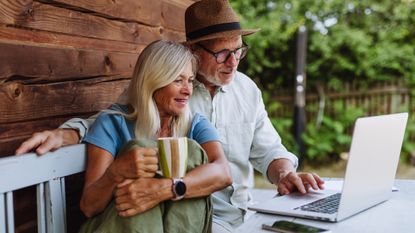 a couple talking at a table while scrolling on a laptop