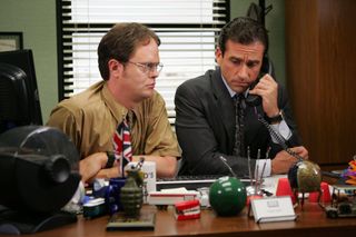 dwight sits by michael at his desk while he's on the phone in The Office