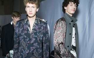 Two male models wearing patterned clothing by Dries Van Noten in various colours.