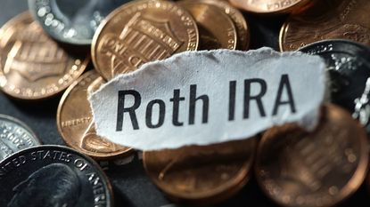 Roth IRA written on a white piece of paper on top of a pile of coins.
