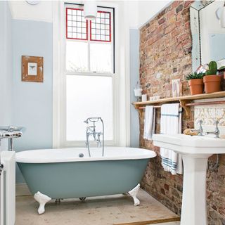 bathroom with red bric and blue wall bathtub window and wash basin