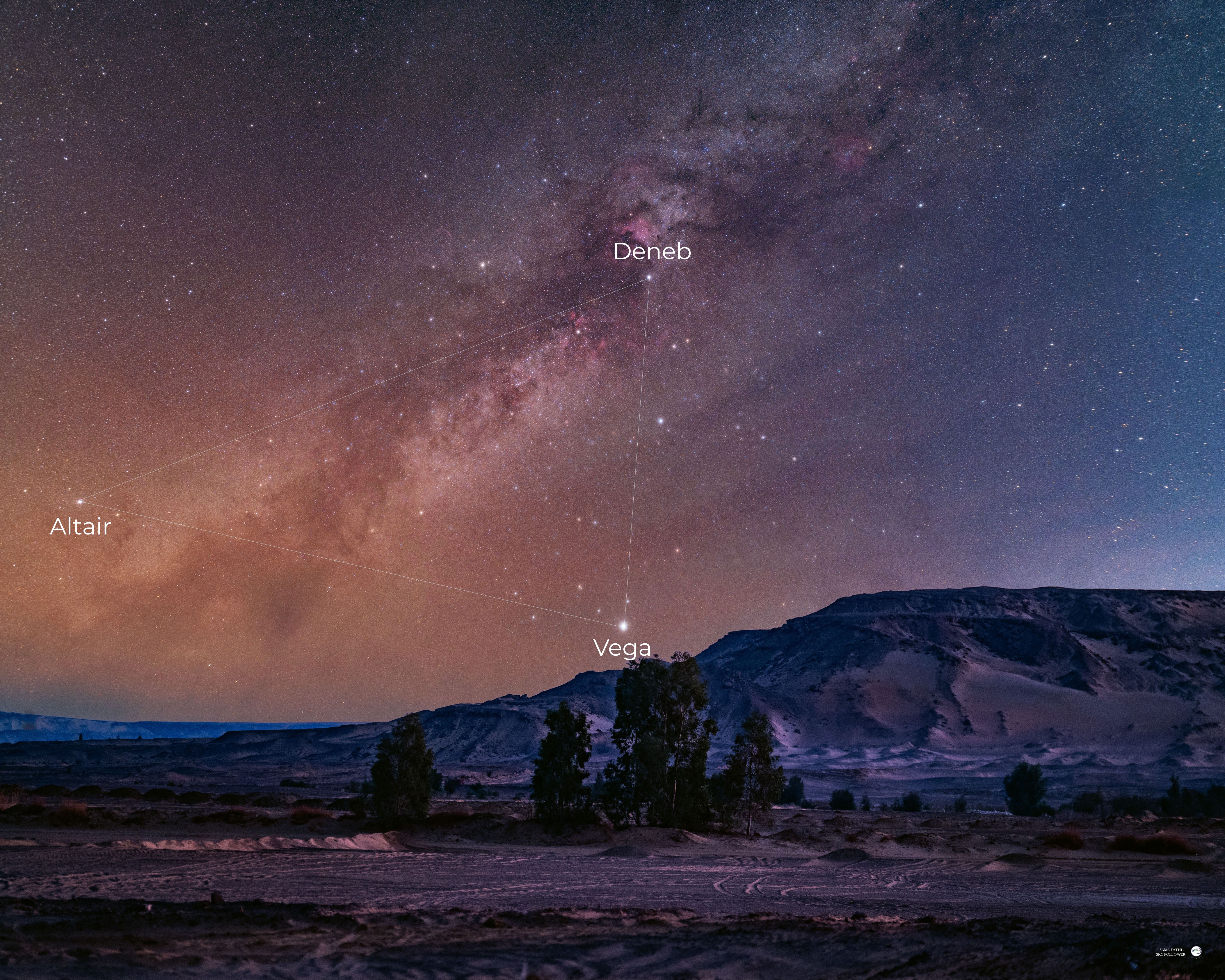 The glowing band of the Milky Way's galactic plane is pictured tumbling diagonally through a starry night sky above a mountainous region.