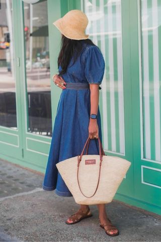 Thandi Maq wearing a denim dress and carrying a beach bag