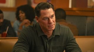 John Cena sitting in restaurant booth in Peacemaker Season 2