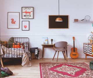 child's bedroom with single black metal bed, small wooden desk with orange pendant shade hanging over