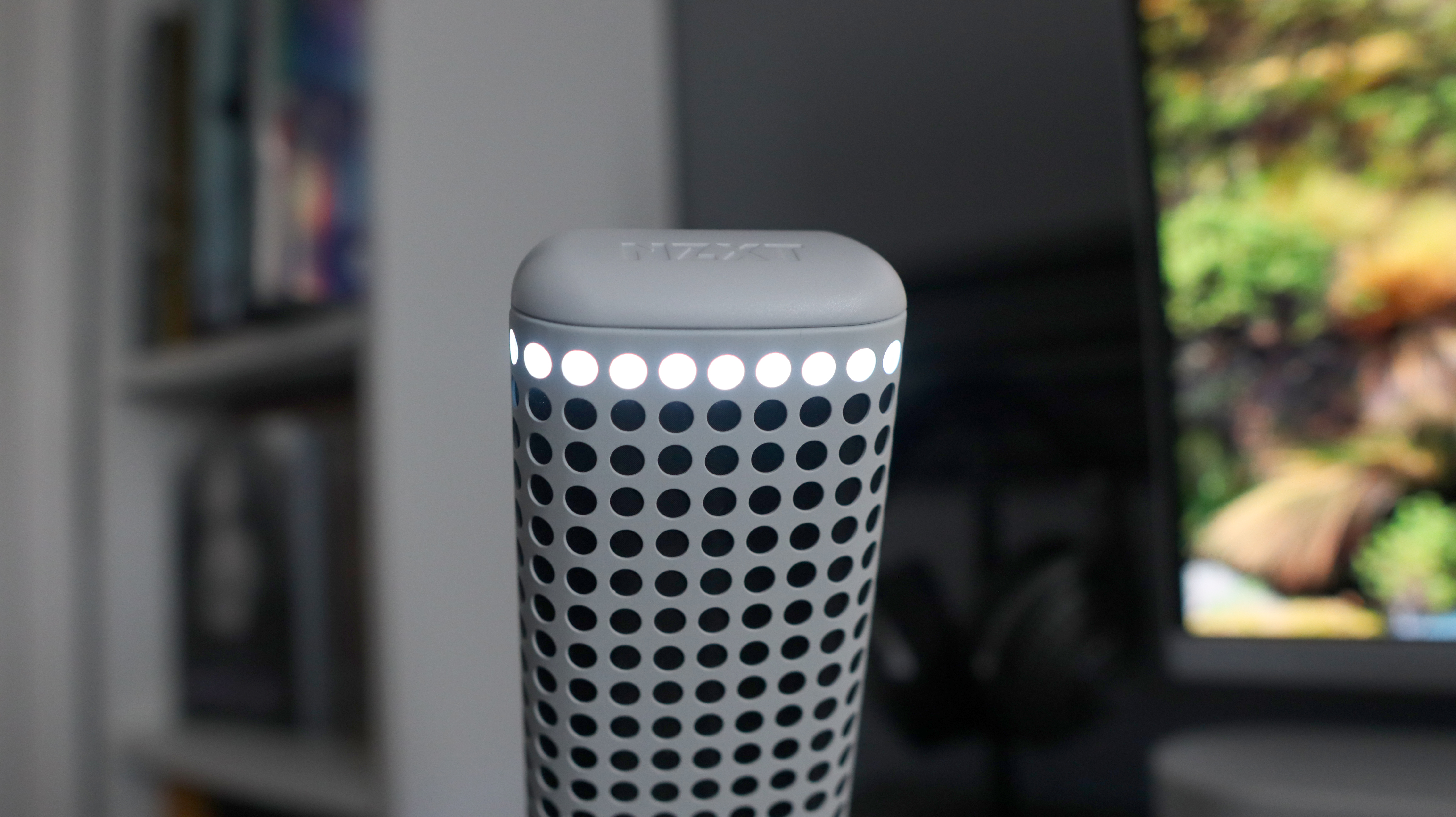 An NZXT Capsule Elite microphone set up on a desk with lighting enabled.