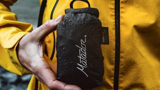 best dry bag: a camper holding the Matador Freerain Waterproof 24L Backpack