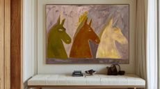 Equestrian-inspired oil painting from Etsy hanging on an entryway wall above a long leather tufted bench