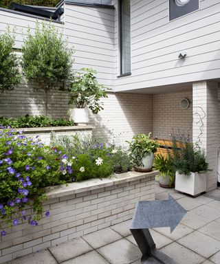 A small courtyard garden with tiered raised beds made of white bricks