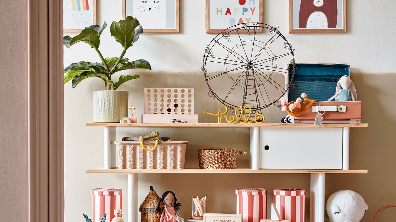 Pink and white open shelving unit in a kids&#039; room, with baskets for organising