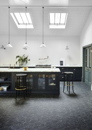 black kitchen with black marble hex vinyl flooring, white shiplap walls, white pendant lights, marble countertops, bar stools