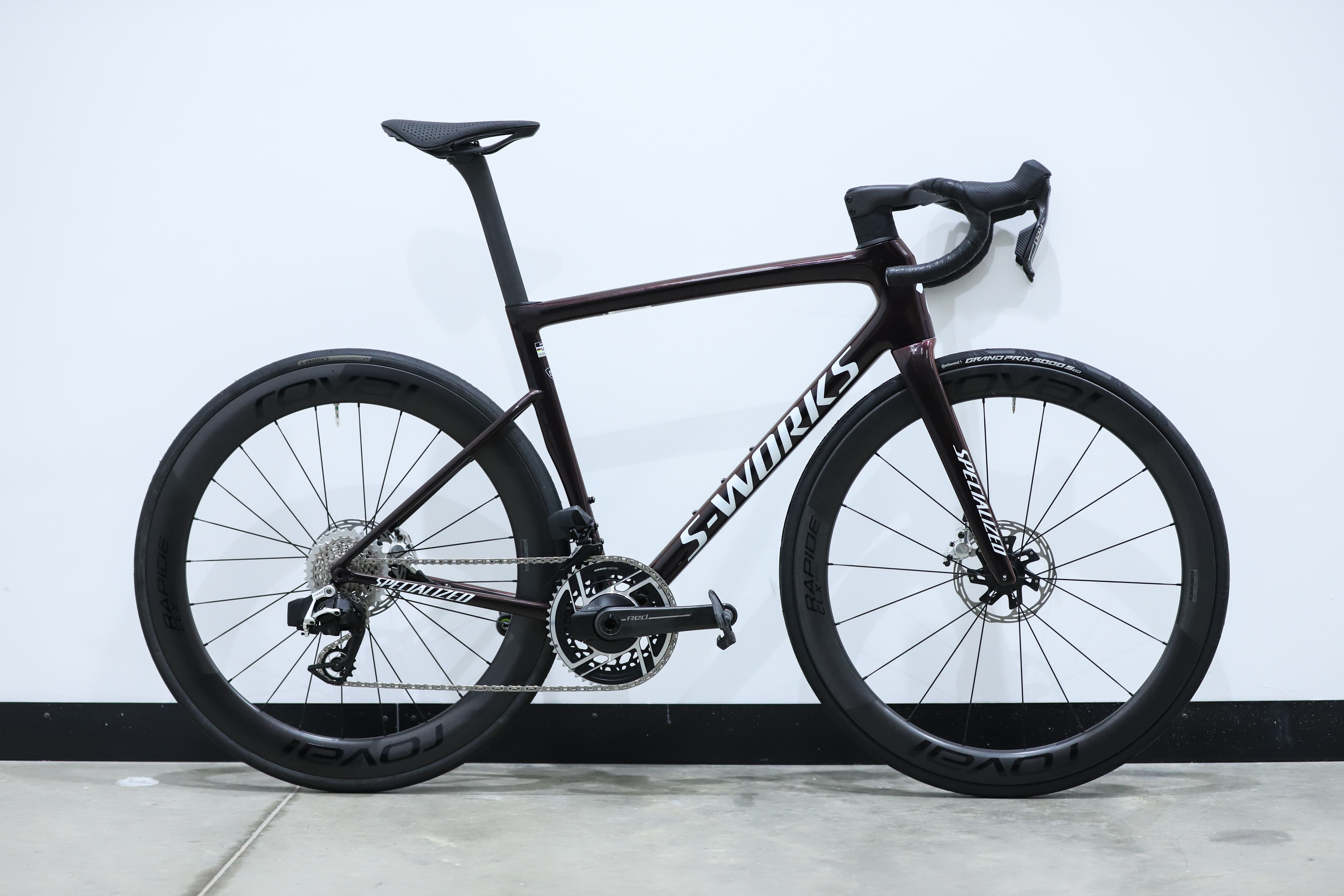 A red Specialized S-Works Tarmac SL8 stands against a white wall