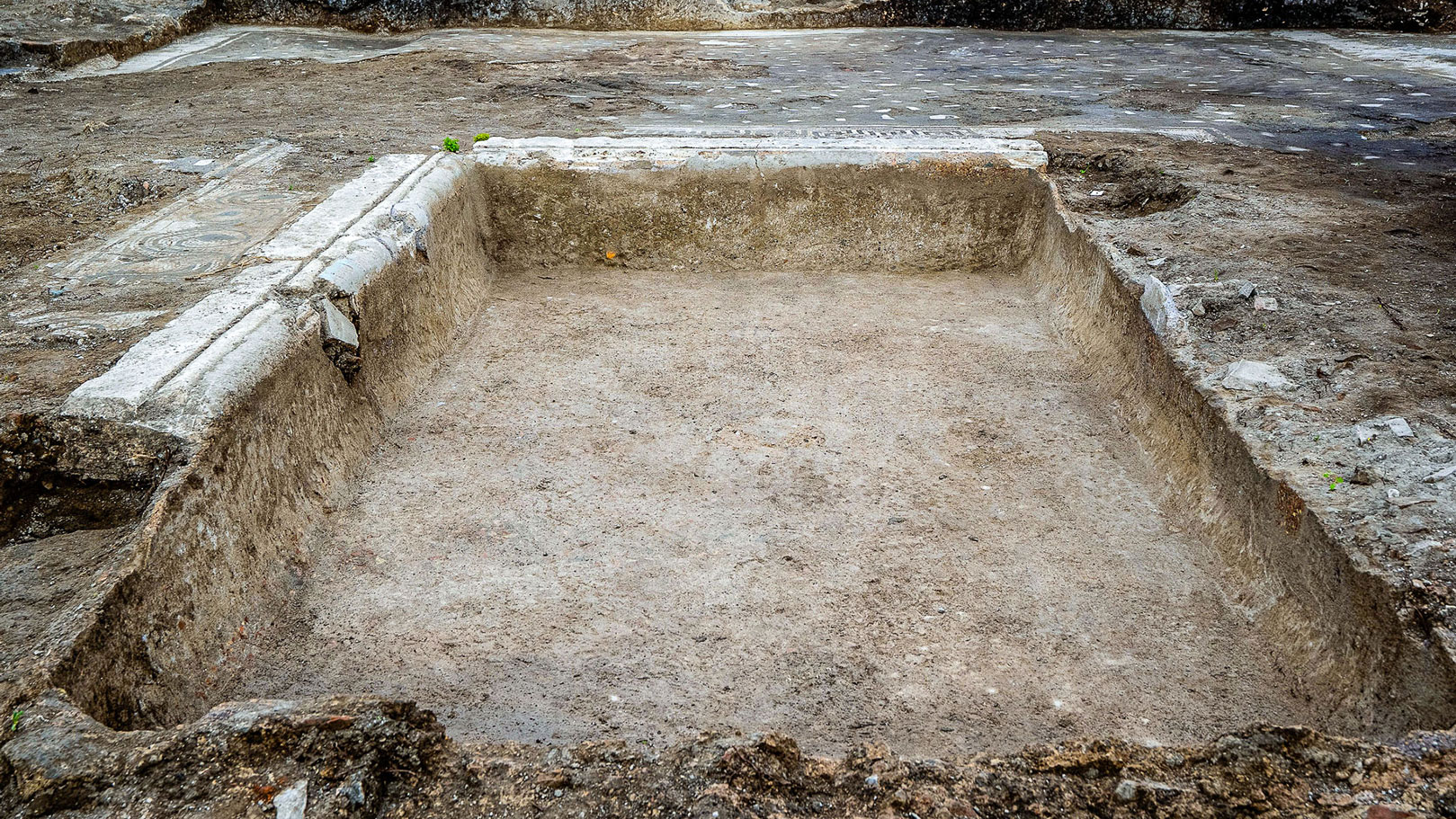 archaeologists work at an ancient Roman site revealing mosaic floors and frescoed walls of a villa