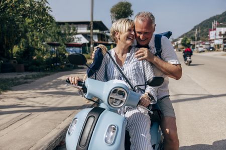 a happy couple riding on an electric scooter