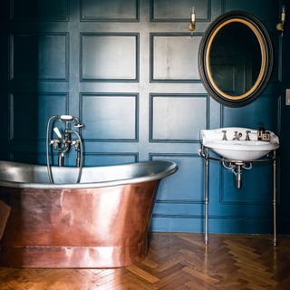 deep blue bathroom with copper bathtub and mirror