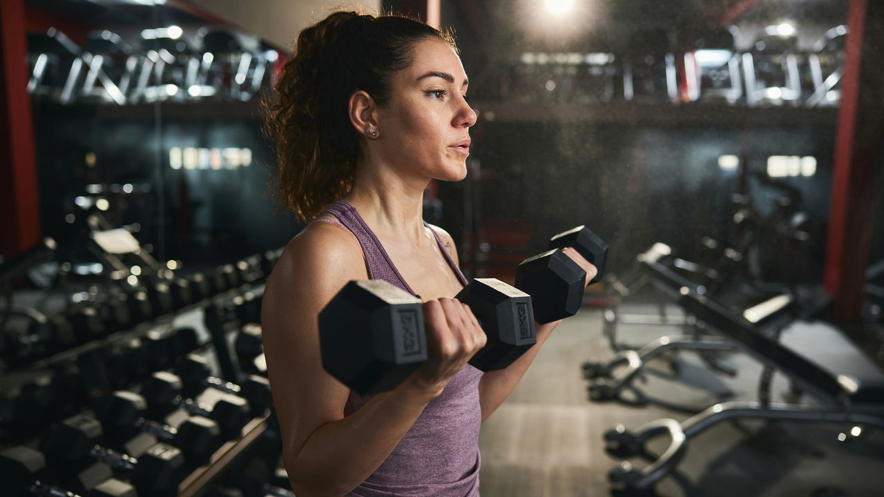 Woman doing a bicep curl in a gym