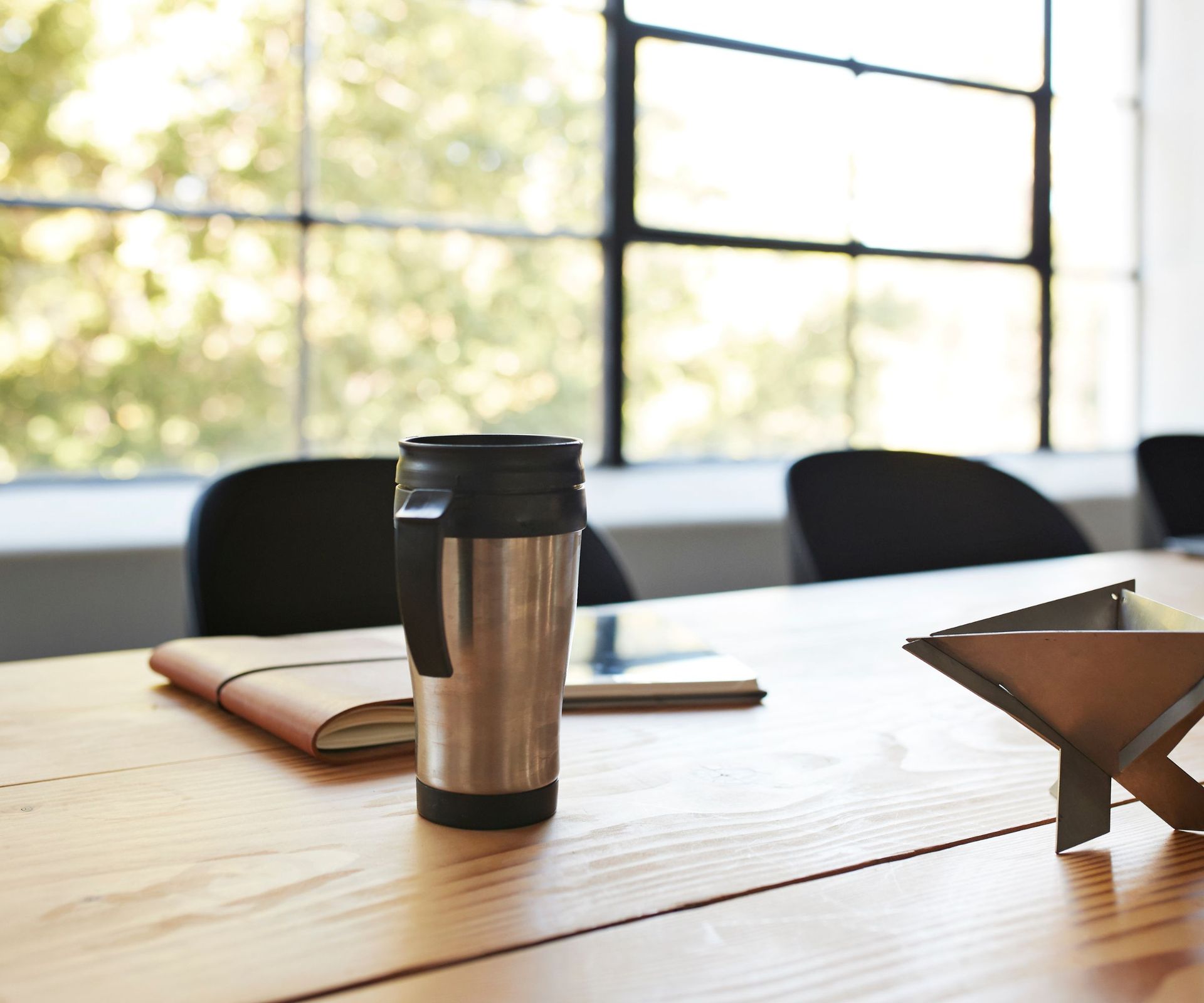 A black and silver travel mug on a desk