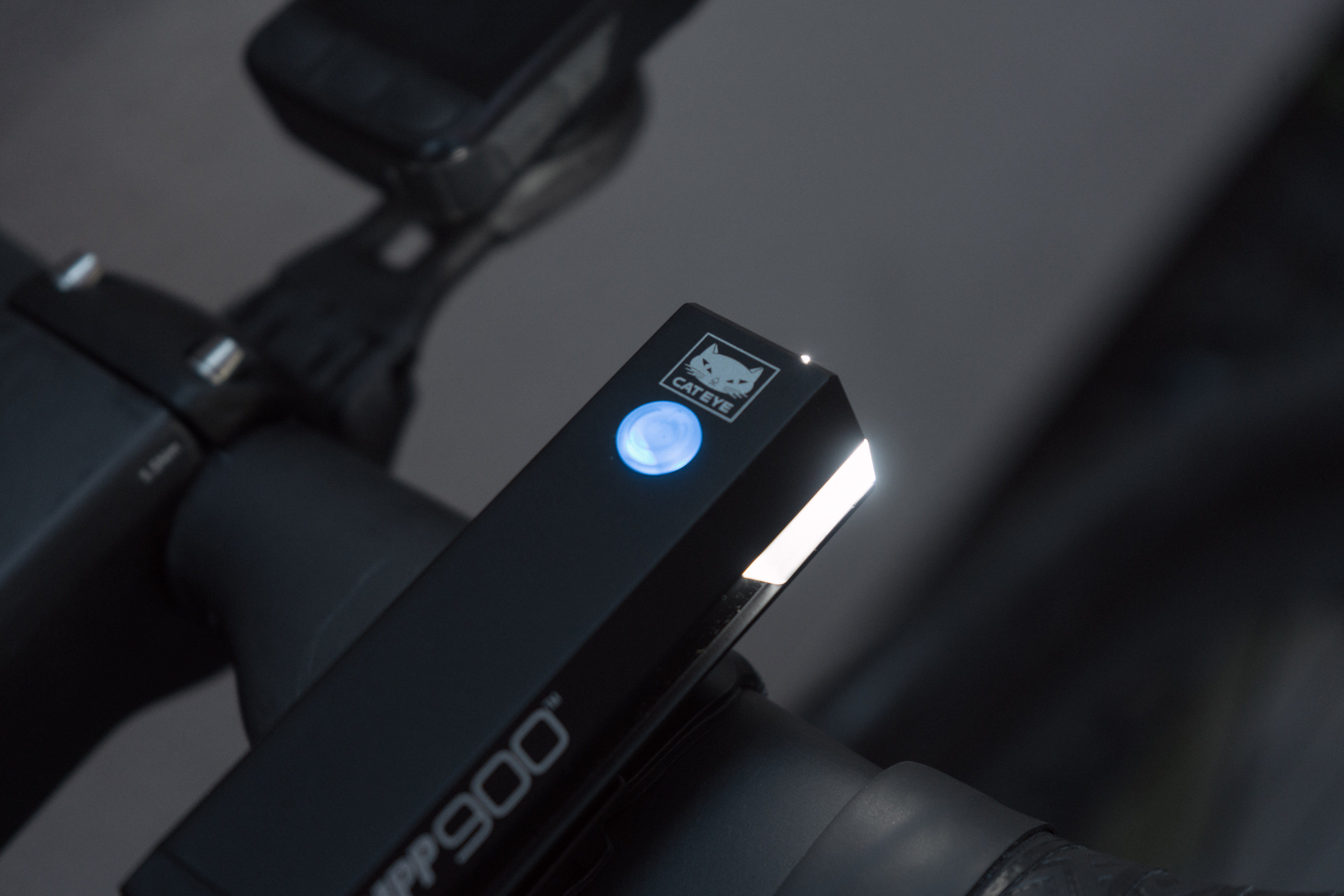 A close up of the upper button of a bike light illuminated blue