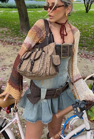 A woman's jean outfit with a strapless denim dress styled with oversize brown belts, an ombré brown cardigan, and a vintage Dior bag.