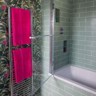 bathroom with banana leaf printed wallpaper tiled walls and bathtub