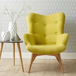 yellow arm chair with grey designed wall and white vase