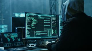 Unknown hacker on a computer in a dark room