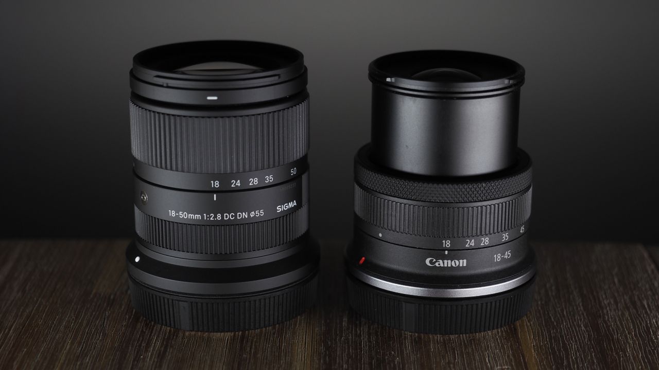 The Sigma 18-50mm f/2.8 DC DN | C Canon RF lens on a wooden surface against a dark background with moody lighting