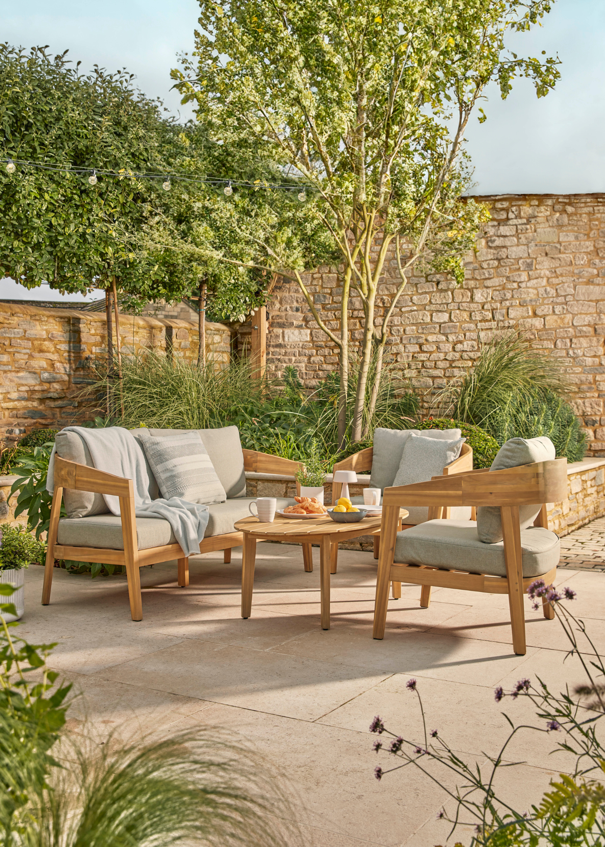 an outdoor dining set in acacia with grey cushioned seating