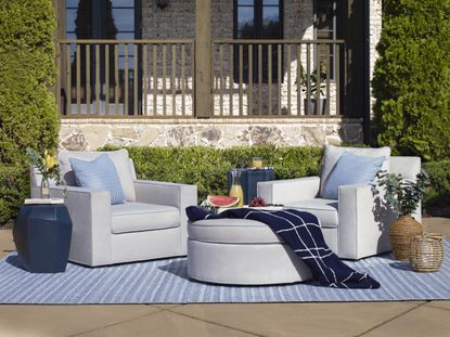 Blue striped outdoor rug, grey armchairs, wicker plant pots