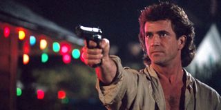 Lethal Weapon Mel Gibson aims a gun next to some Christmas lights