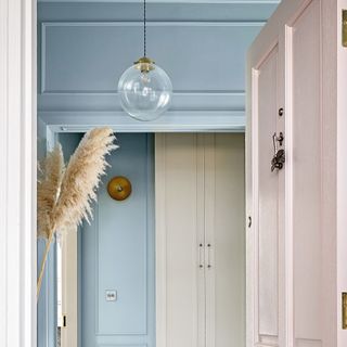 Hallway with blue paint on walls and skirting boards with pink door
