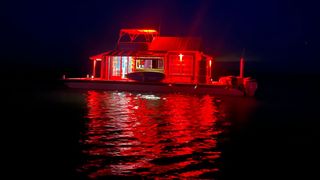 a floating boat with a cabin on and red lights.