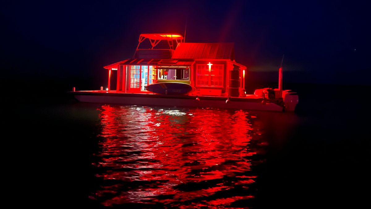 a floating boat with a cabin on and red lights.