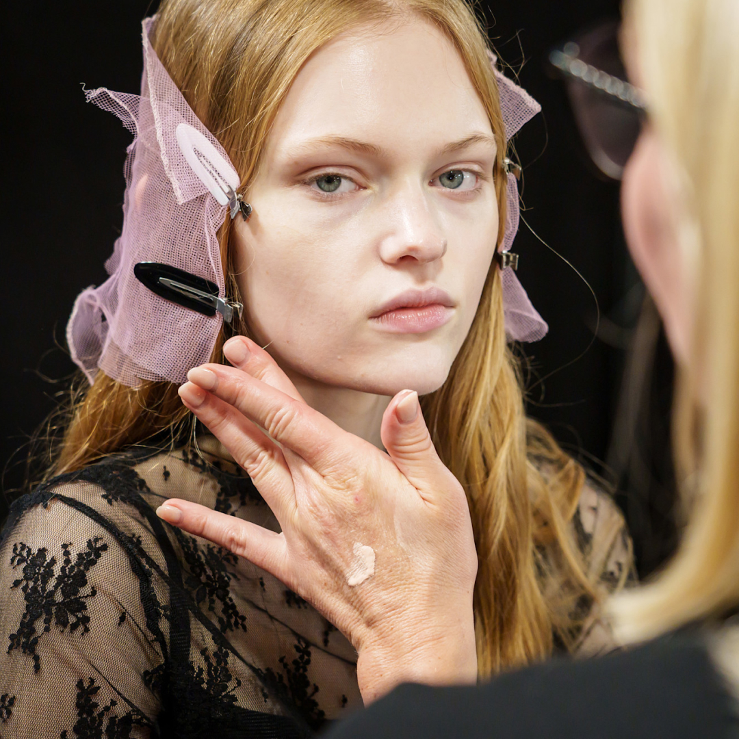 Woman applying face lotion to model backstage at Sacai spring 2025 fashion show 