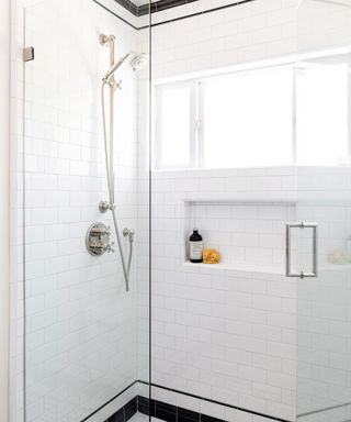 A black and white walk-in shower with a showerhead and a shelf with toiletries