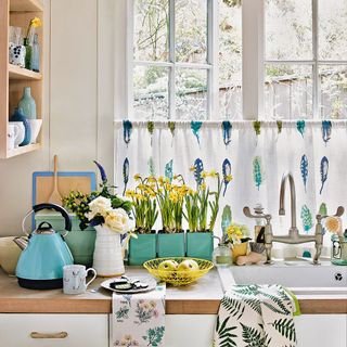 kitchen with washing area looking out to kitchen with planted daffodils and open shelving