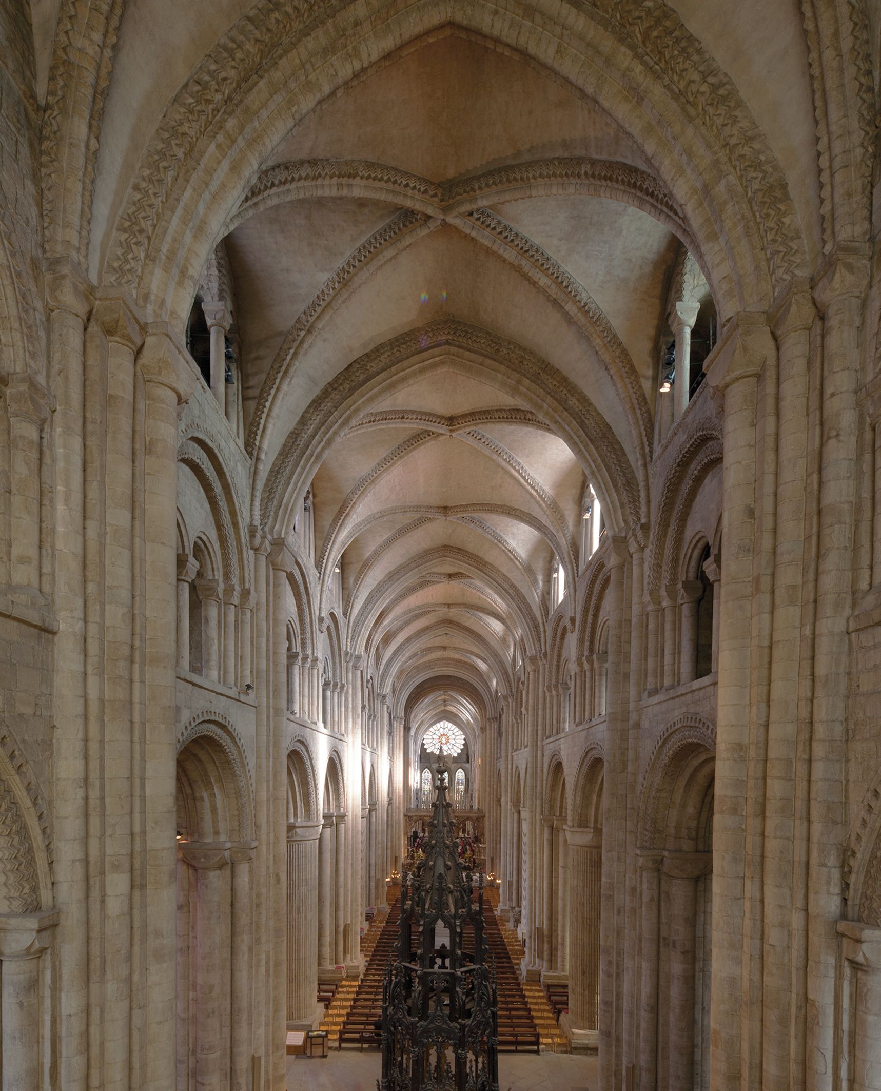 Interior view of a grand cathedral, showcasing its intricately vaulted ceilings, stone arches, and a central ornamental feature
