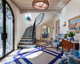 Grand entryway with blue mosaic tiled flooring and blue accent chairs