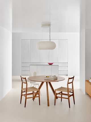 Table and chairs in white space of Reform Kitchens New York showroom