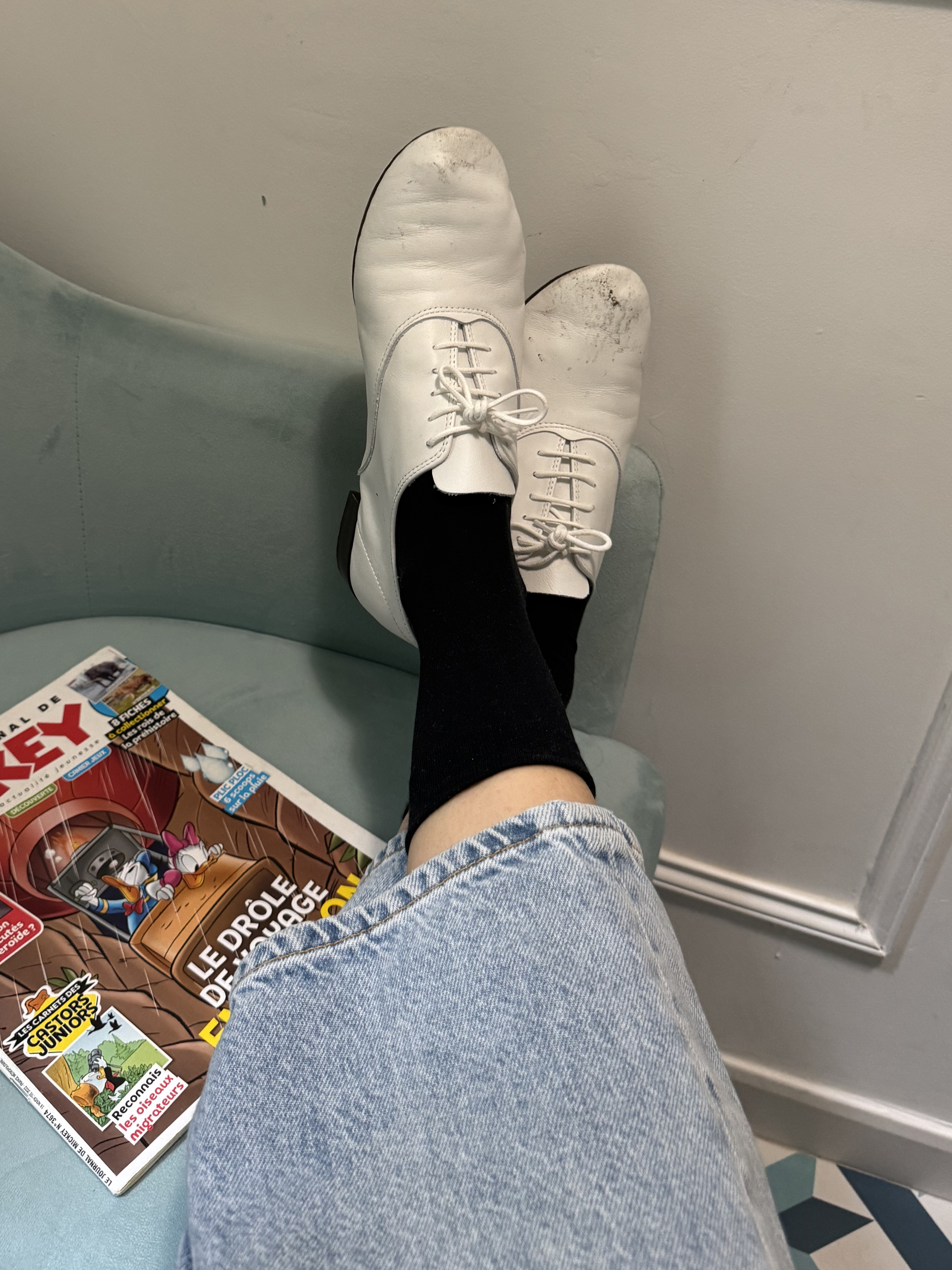 Eugenie Trochu wears worn-in white Repetto Zizzi lace-up oxfords, black socks and jeans