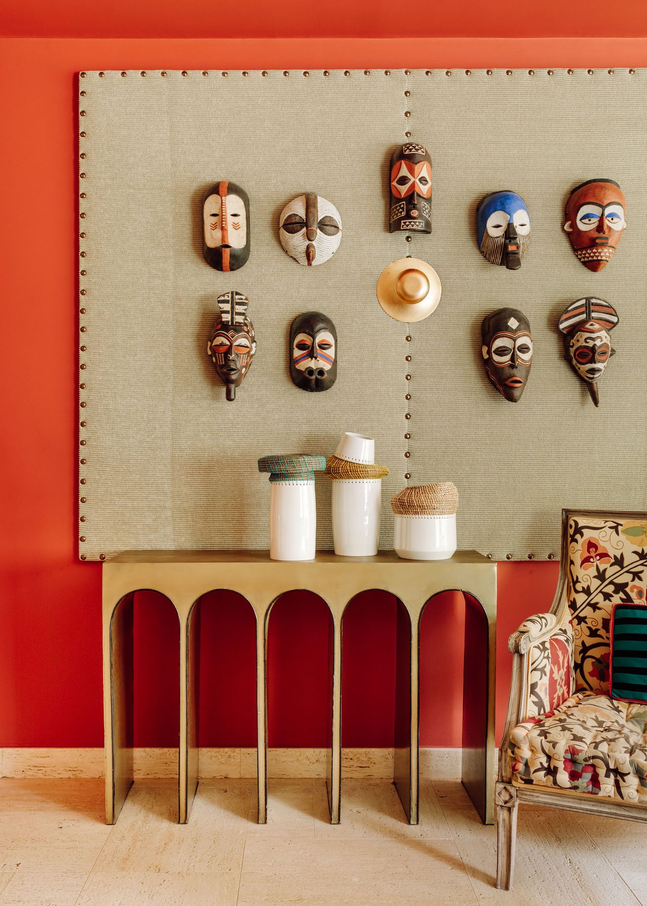 Contemporary display with red wall, stone pin board and traditional painted mask display